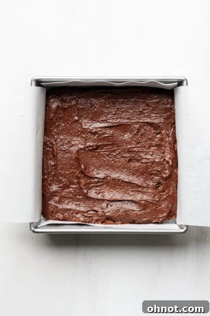 Smooth, glossy brownie dough poured into a parchment-lined pan