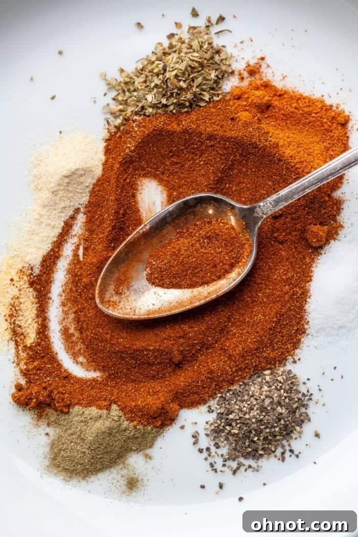 Gluten Free Cajun seasoning on a white plate with a spoon, showcasing its rich color and texture.