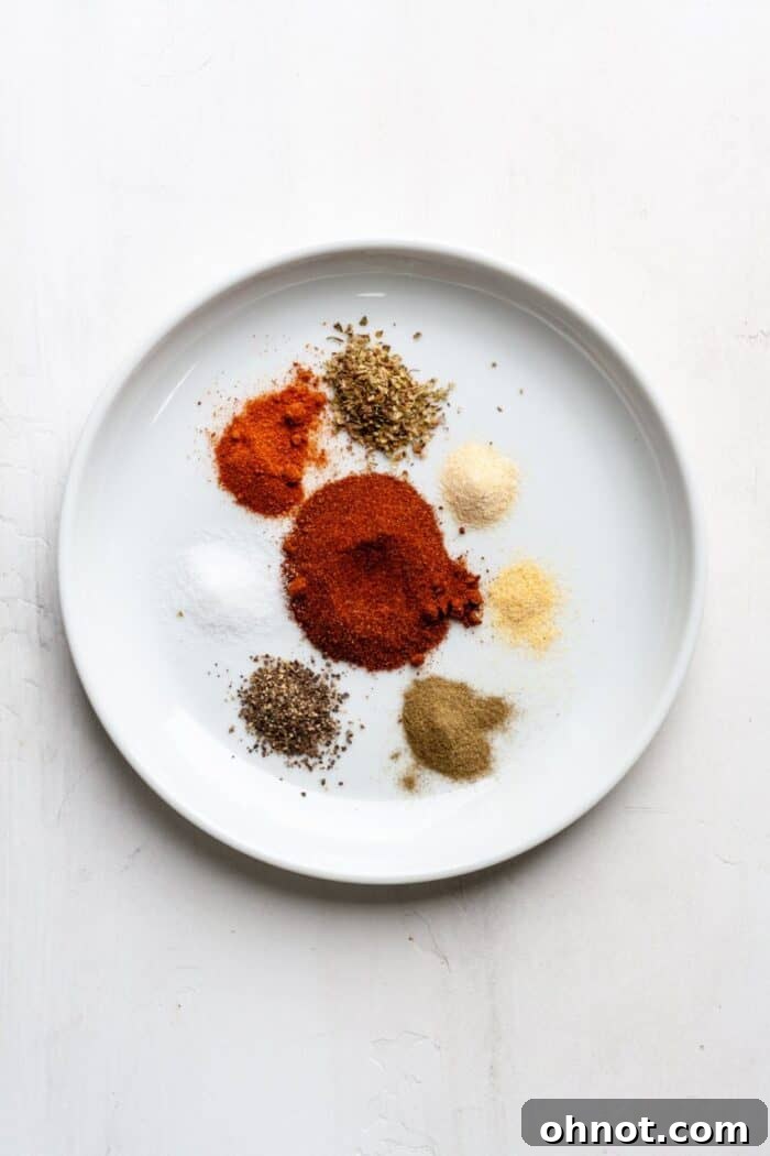Individual spices laid out on a white surface, ready to be mixed for homemade Whole30 Cajun seasoning.