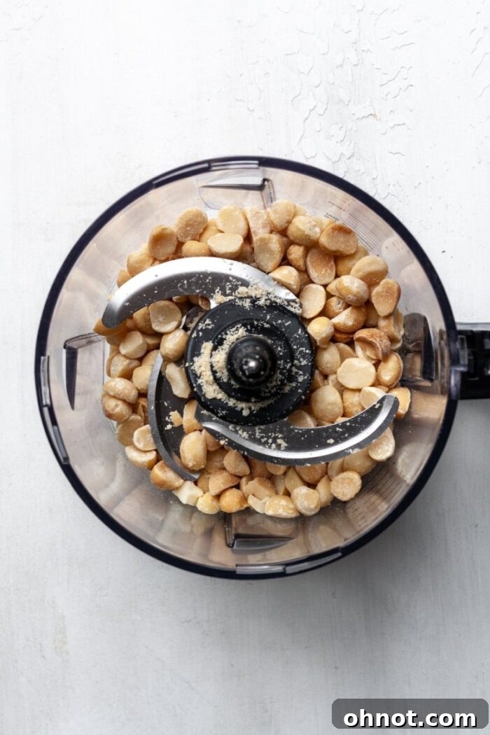 Close-up of macadamia nuts being processed in a blender, starting to break down into a coarse mixture.