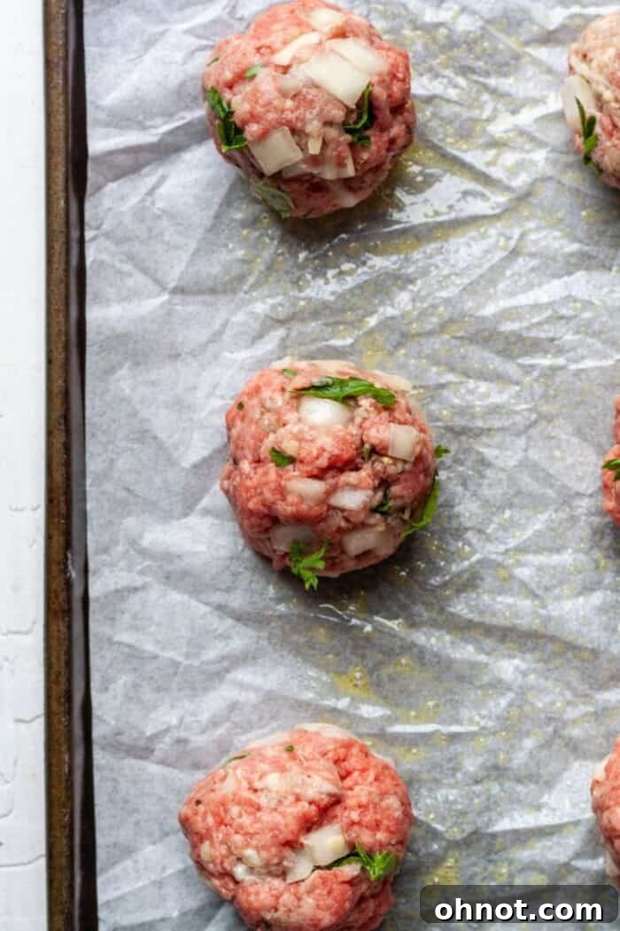Uncooked meatballs without breadcrumbs arranged on a baking sheet