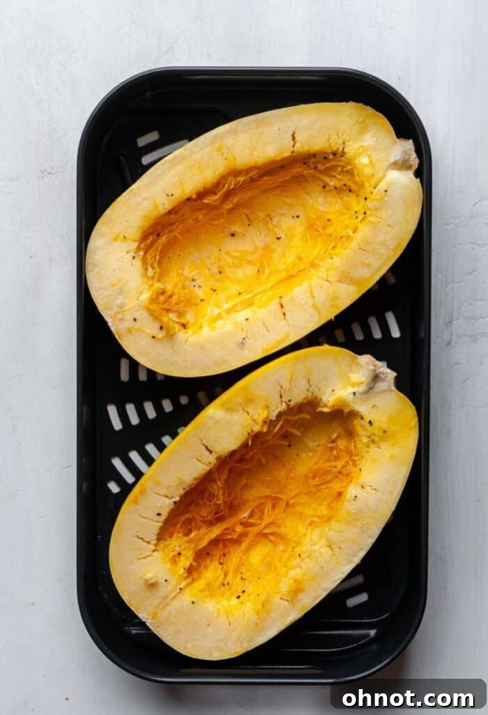 Seasoned spaghetti squash halves in an air fryer basket