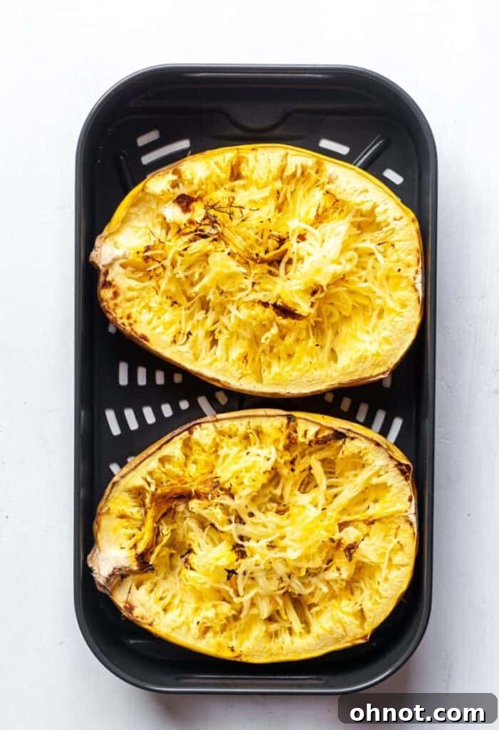 Cooked spaghetti squash in an air fryer basket, ready to be shredded