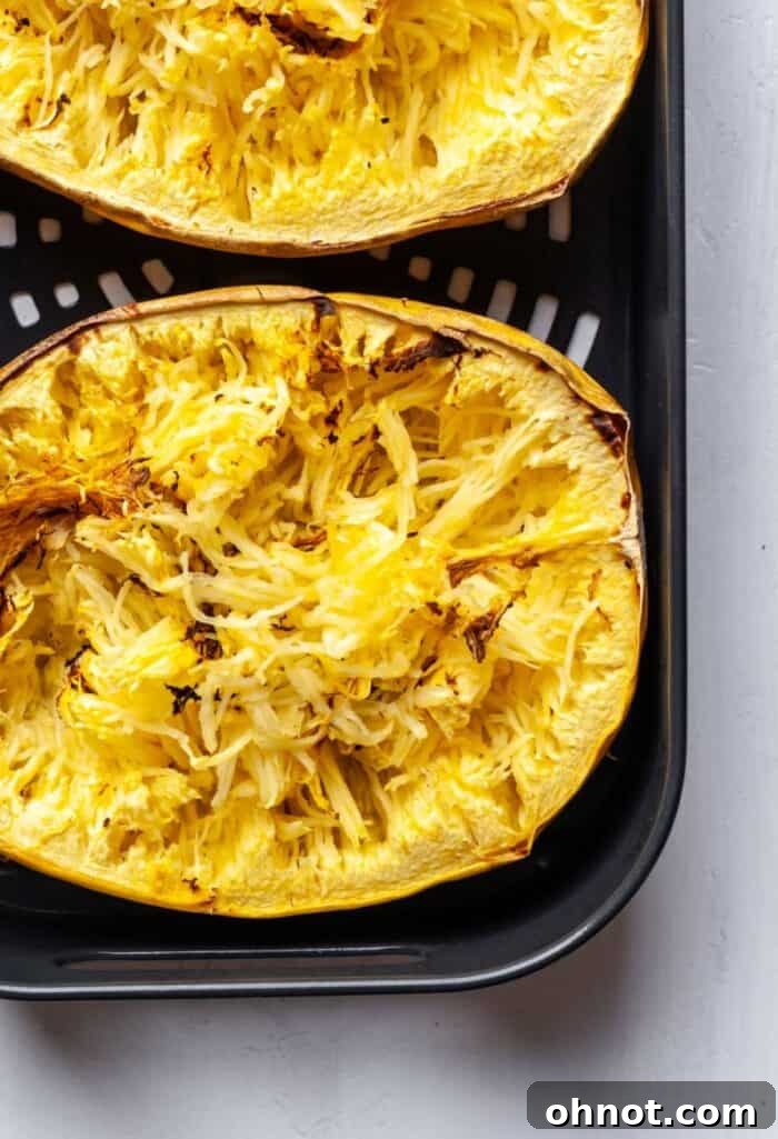 Shredded spaghetti squash in an air fryer basket with two forks