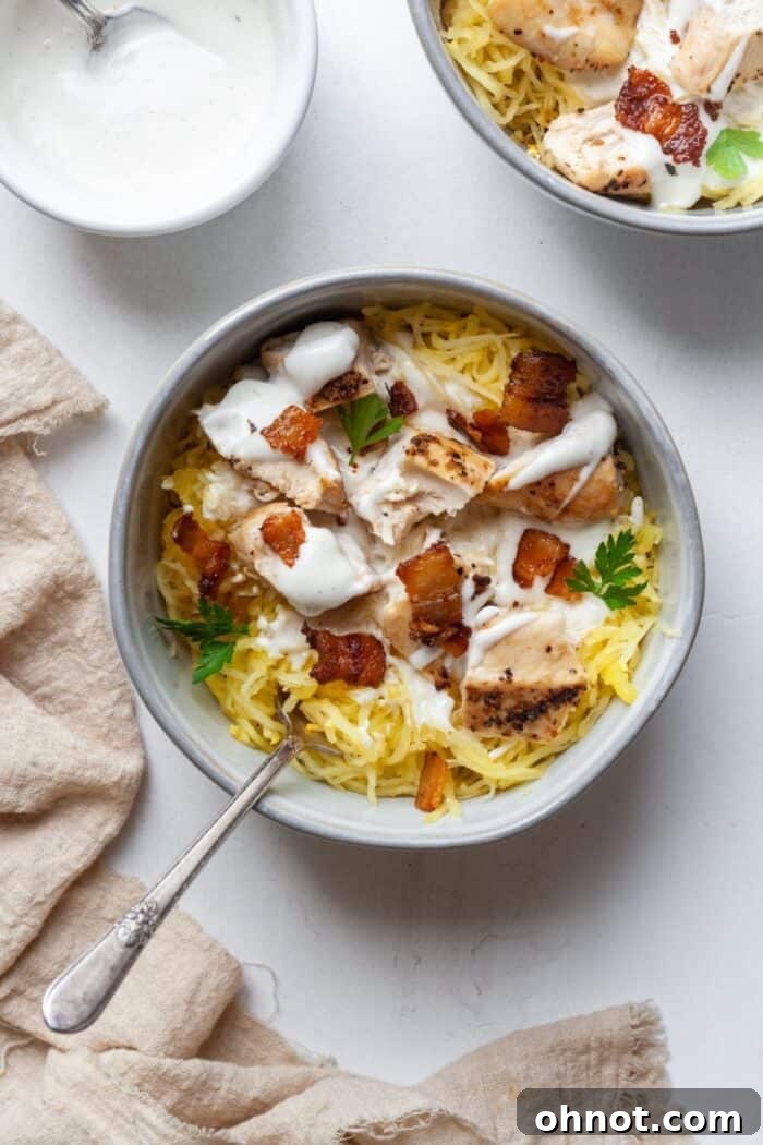 A vibrant bowl of spaghetti squash mixed with tender chicken, crispy bacon, and creamy Ranch dressing, garnished with fresh herbs.