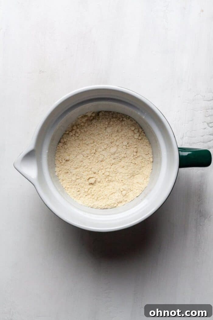 A mixing bowl containing sifted dry ingredients for gluten-free strawberry muffins.