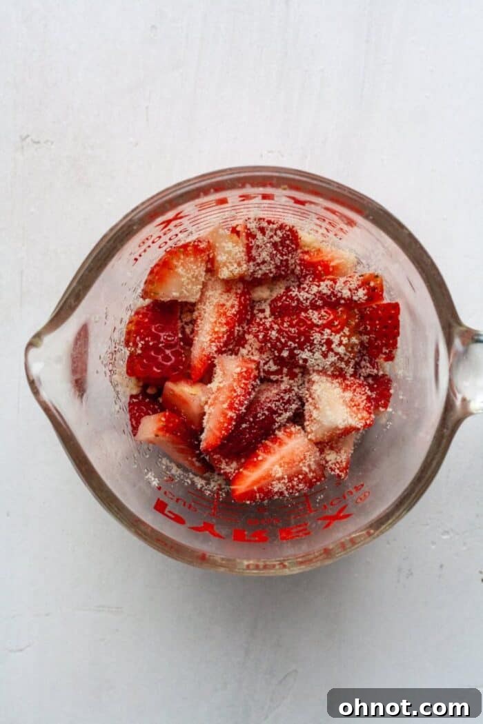 Freshly diced strawberries coated with a light dusting of almond flour on a cutting board.