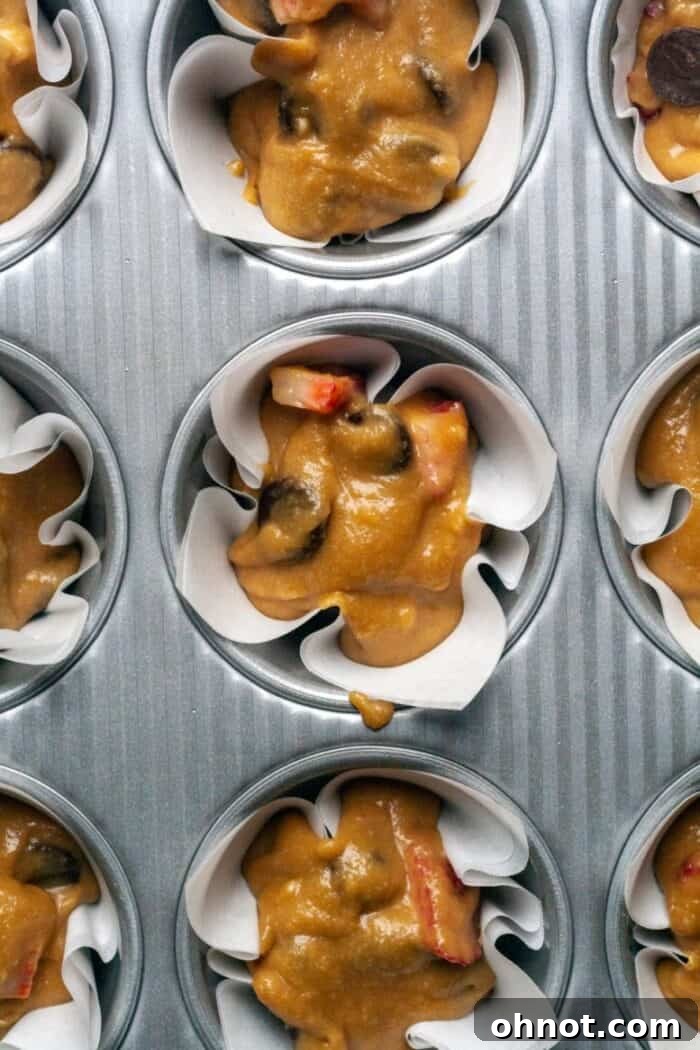 Paleo strawberry muffin batter scooped into paper liners in a muffin tin, ready for baking.