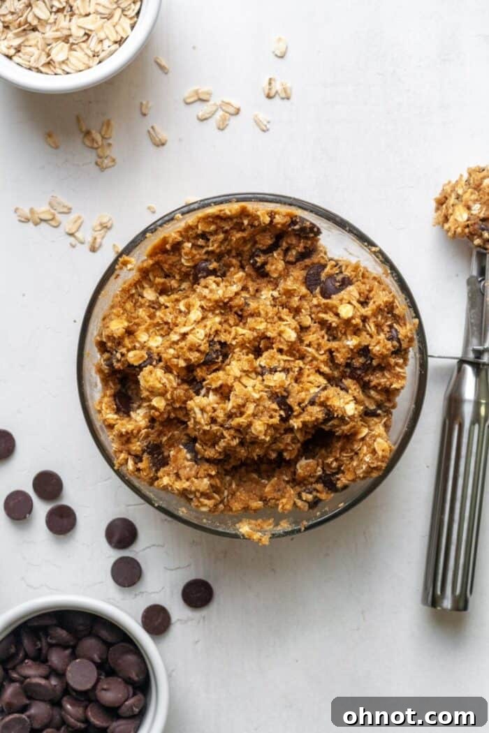 Glass bowl filled with uncooked almond flour oatmeal cookie dough, ready for baking.