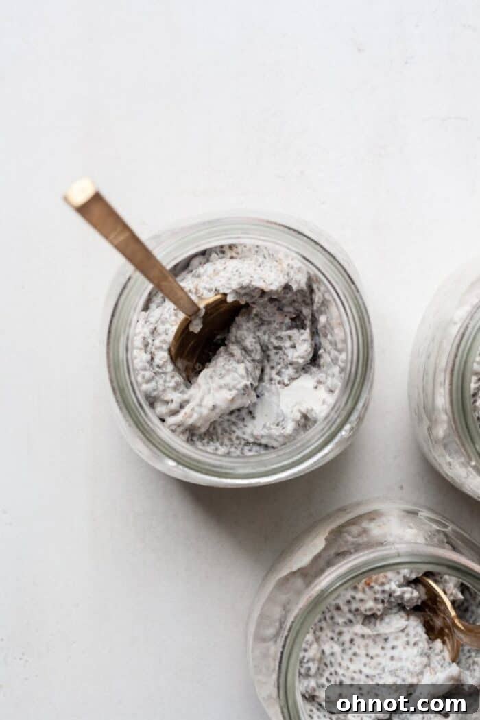 Vegan chia pudding with a spoon in a glass jar, showing its creamy texture.