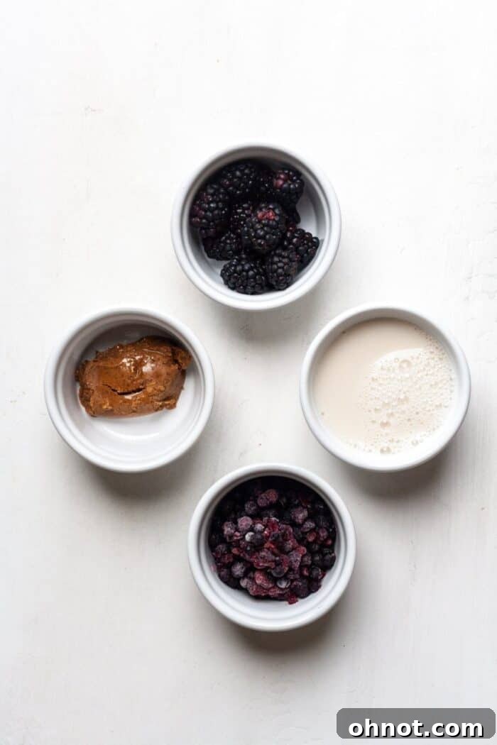 A selection of fresh ingredients including blueberries, blackberries, and almond butter, ready for blending into a healthy smoothie.