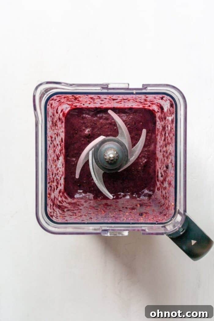 The vegan blueberry smoothie actively blending in a high-speed blender, creating a vortex of purple goodness.