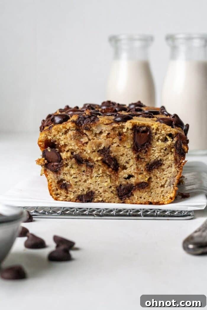 A slice of gluten-free zucchini banana bread with visible chocolate chips and a moist interior, artfully presented.