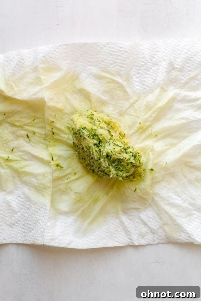 A tightly wrung-out ball of grated zucchini after all excess moisture has been removed, demonstrating proper preparation.