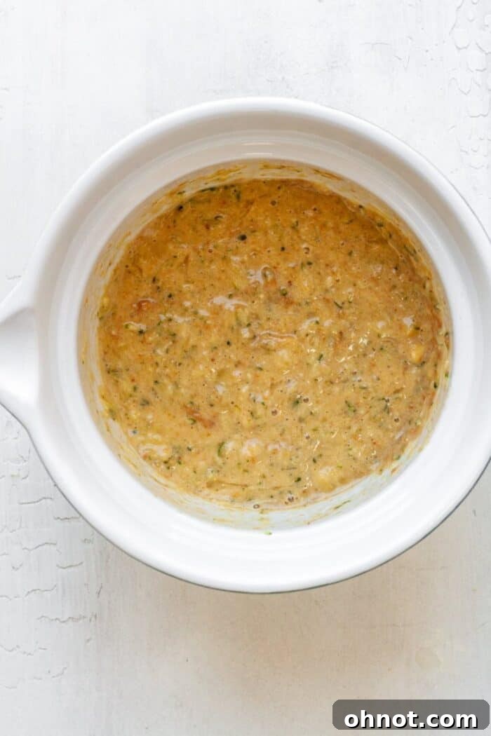 Zucchini banana bread dough in a bowl after dry ingredients have been added, showing a thick, cohesive mixture.