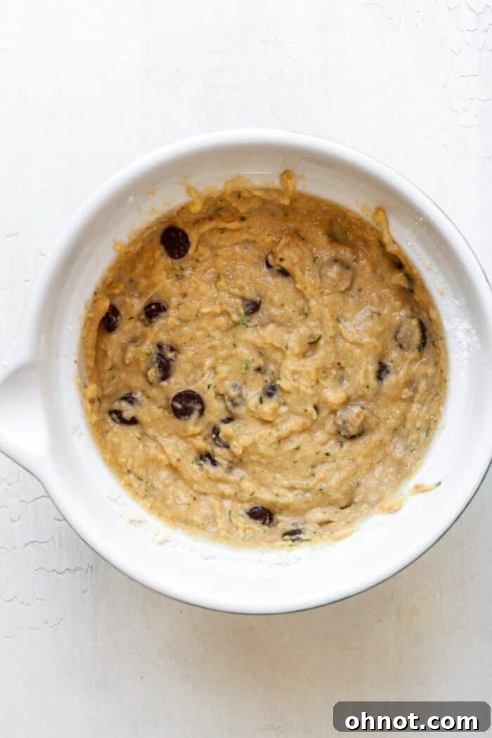 Zucchini bread batter in a mixing bowl with chocolate chips folded in, ready for transfer to the pan.
