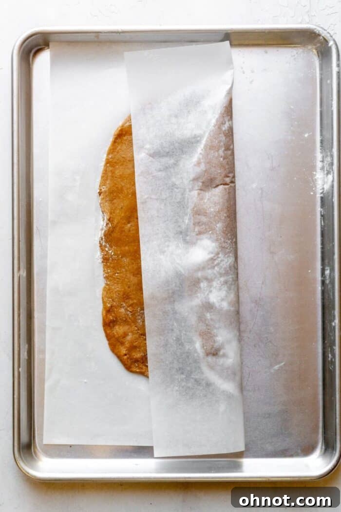 Using parchment paper to carefully fold one side of the cookie dough over the fig filling.