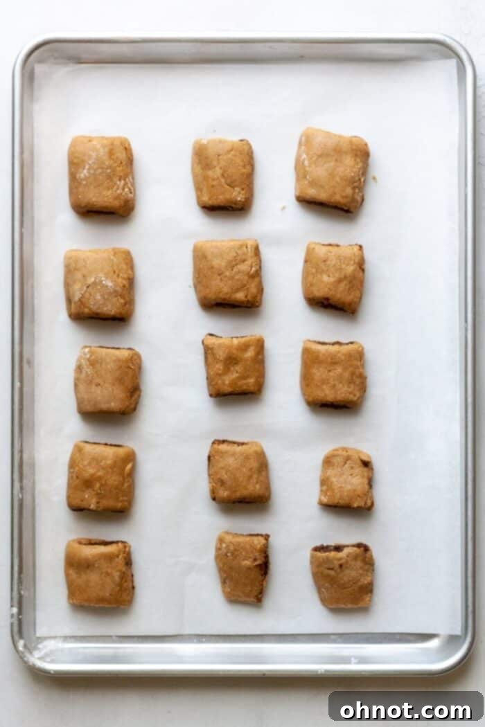 Unbaked fig newtons neatly arranged on a baking pan, ready to go into the oven.