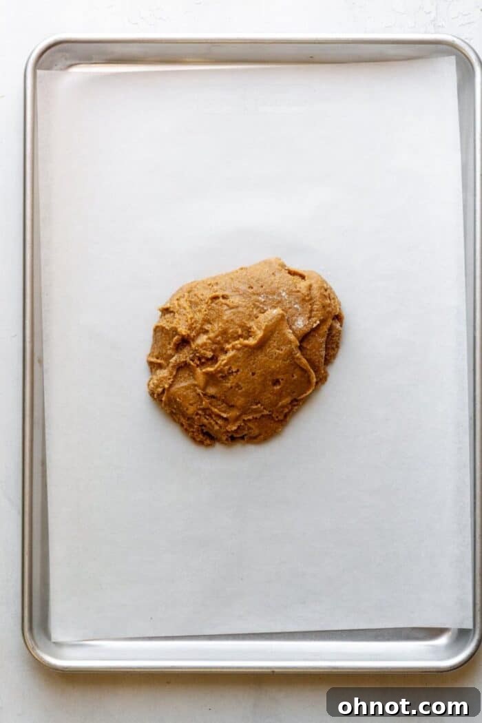 A smooth ball of fig newton dough resting on a parchment-lined baking sheet.