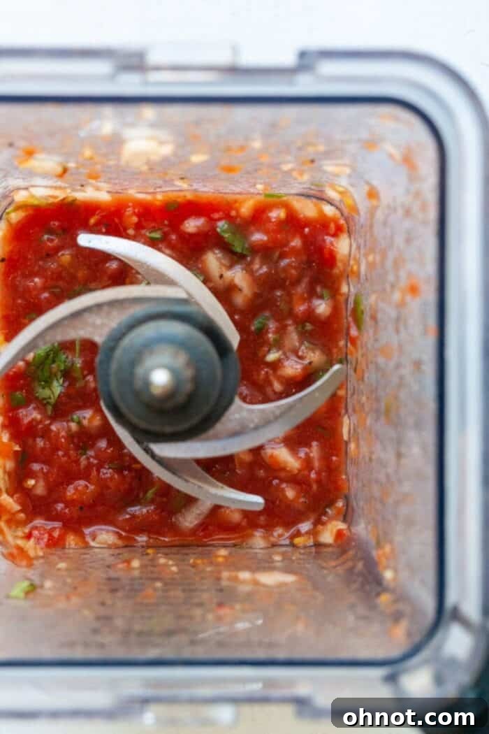 Blender with blended vegetables forming salsa