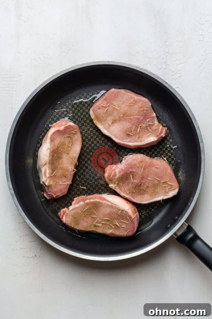 Pork chops cooking in a hot skillet, showing a developing sear