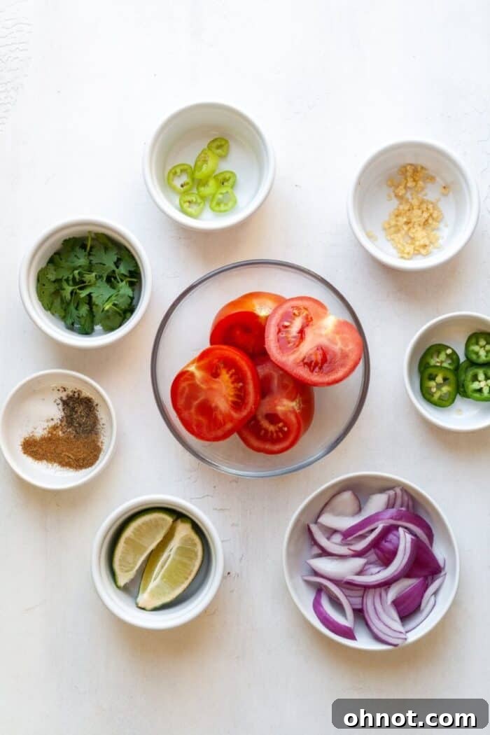 A vibrant and appealing selection of fresh salsa ingredients neatly arranged on a rustic wooden cutting board, including plump red tomatoes, finely chopped red onion, bright green jalapeños and chili, fresh cilantro sprigs, and half-cut limes, all ready for preparation.