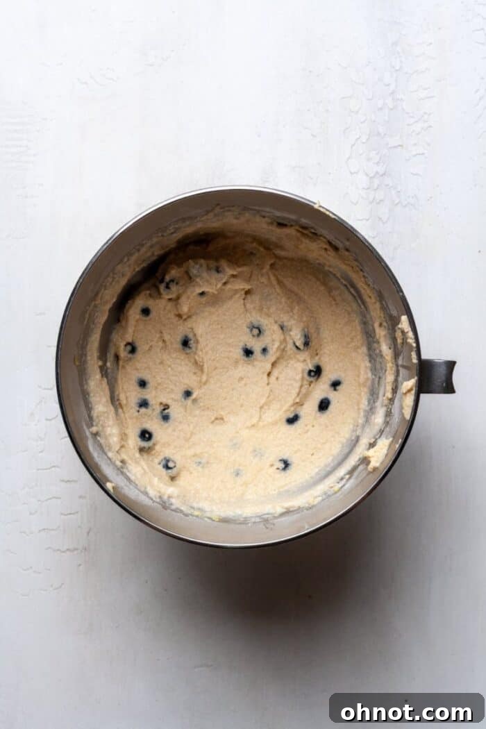 Vibrant blueberry muffin batter in a bowl, with fresh blueberries gently folded in, showcasing the delicious blend for gluten-free baking.