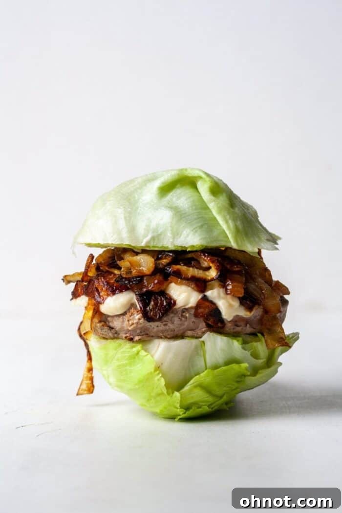 A completed Whole30 turkey burger with a lettuce bun, topped with garlic aioli and caramelized onions