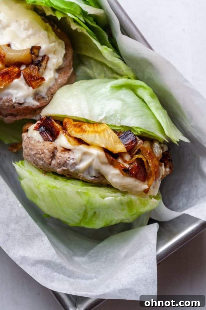 A close-up of a Keto turkey burger, featuring crisp lettuce, sweet caramelized onions, and a juicy patty