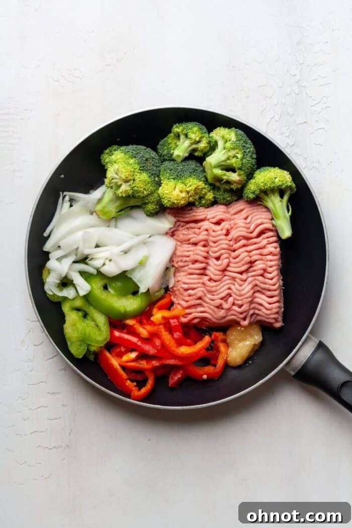Ground turkey and mixed vegetables cooking in a skillet.