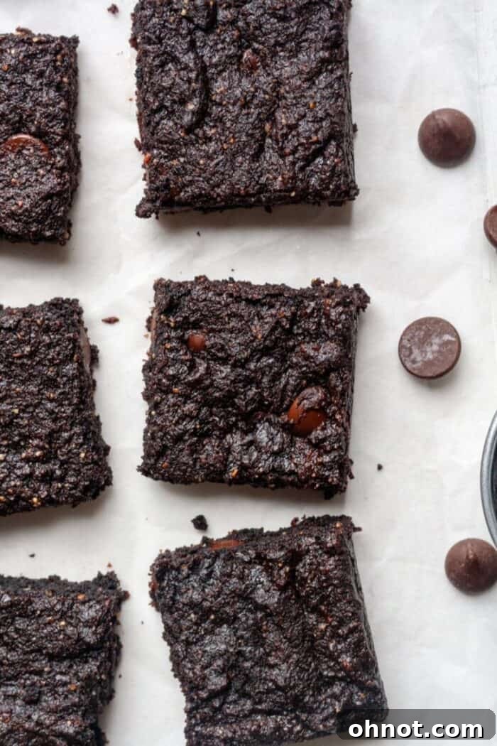 A stack of eggless brownies with visible chocolate chips, dusted lightly with cocoa powder