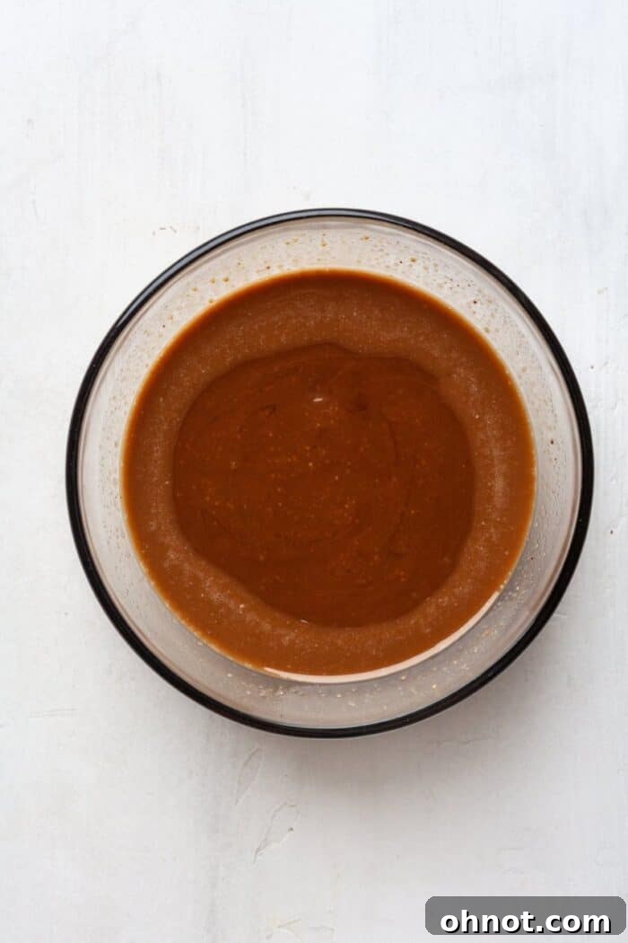Smooth, melted dark chocolate in a glass bowl, glistening beautifully