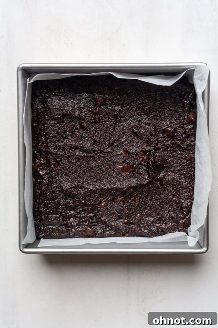 Smooth chocolate batter spread evenly in a parchment-lined baking pan