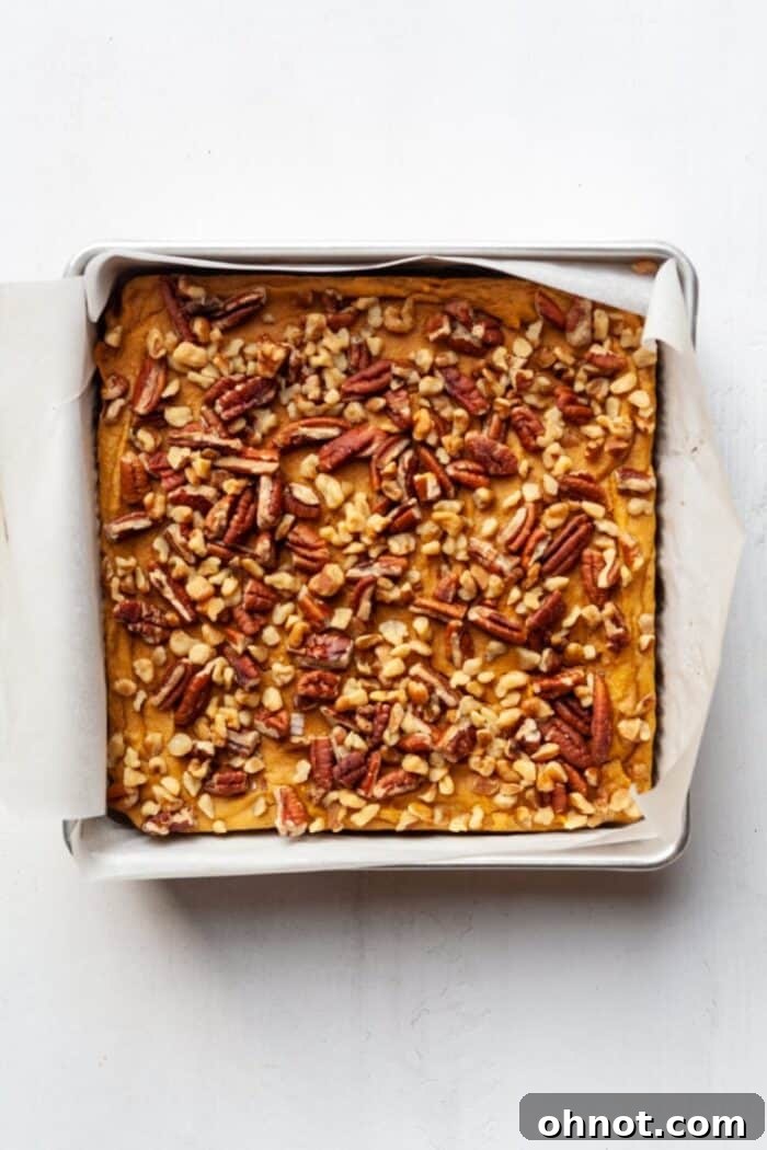 Chilled sweet potato blondies, garnished with walnuts and pecans, waiting to be sliced.