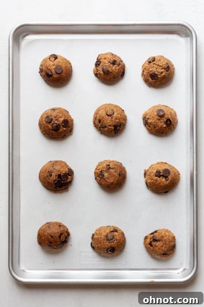 Portioned vegan cookies on a baking pan lined with parchment paper