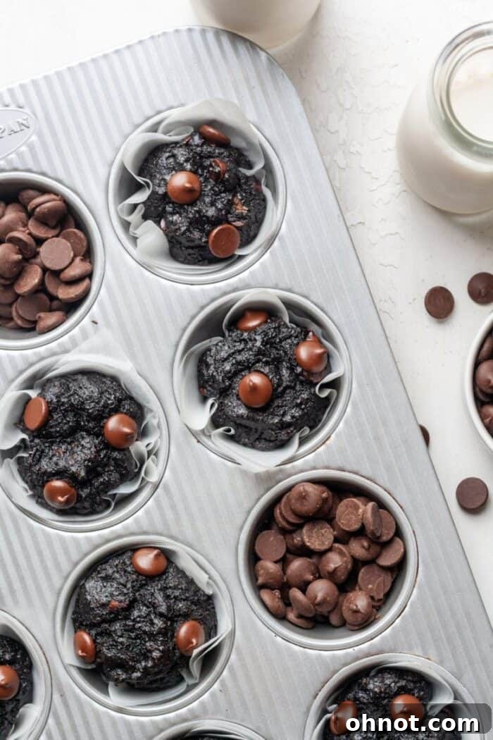 Luscious gluten-free chocolate zucchini muffins arranged neatly in a silver muffin pan, highlighting their perfect golden-brown tops and rich texture.
