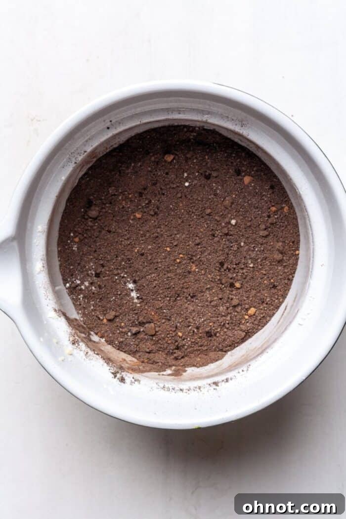 A glass mixing bowl containing all the dry ingredients – flours, cocoa, baking soda, and salt – perfectly blended together.