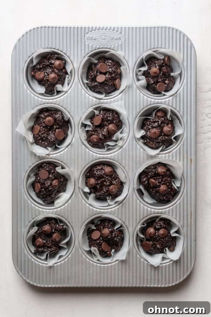 A muffin pan neatly filled with the double chocolate zucchini muffin batter, perfectly portioned and ready for baking.