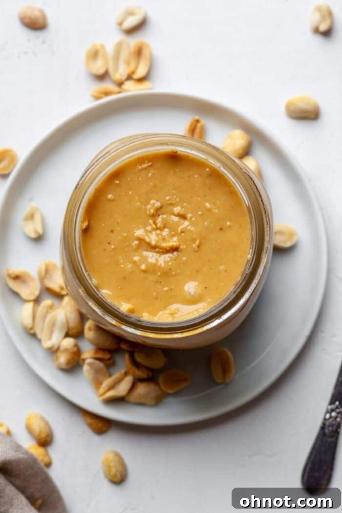 Freshly made Vitamix peanut butter in a clear glass jar, showcasing its smooth and creamy texture.