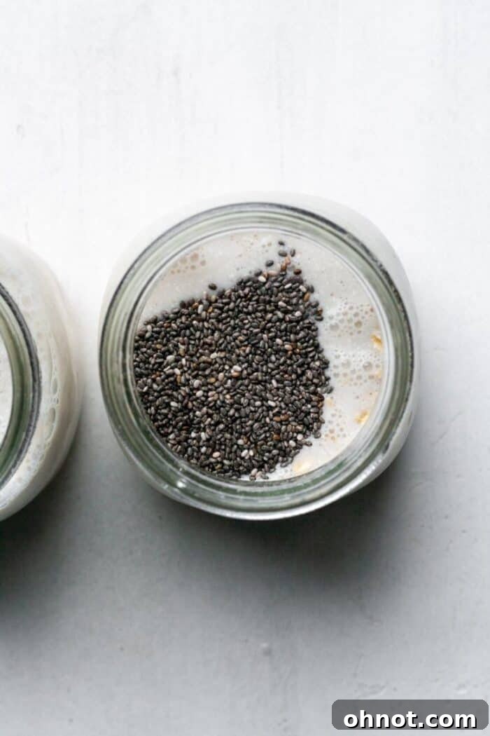 Chia seeds added to oats and almond milk in a jar