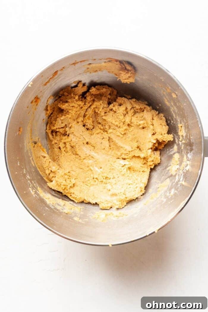 Wet ingredients being added to the dry mix in a bowl, forming pumpkin cookie dough.