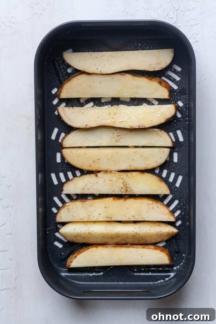 Air fryer basket filled with seasoned potatoes in a single layer