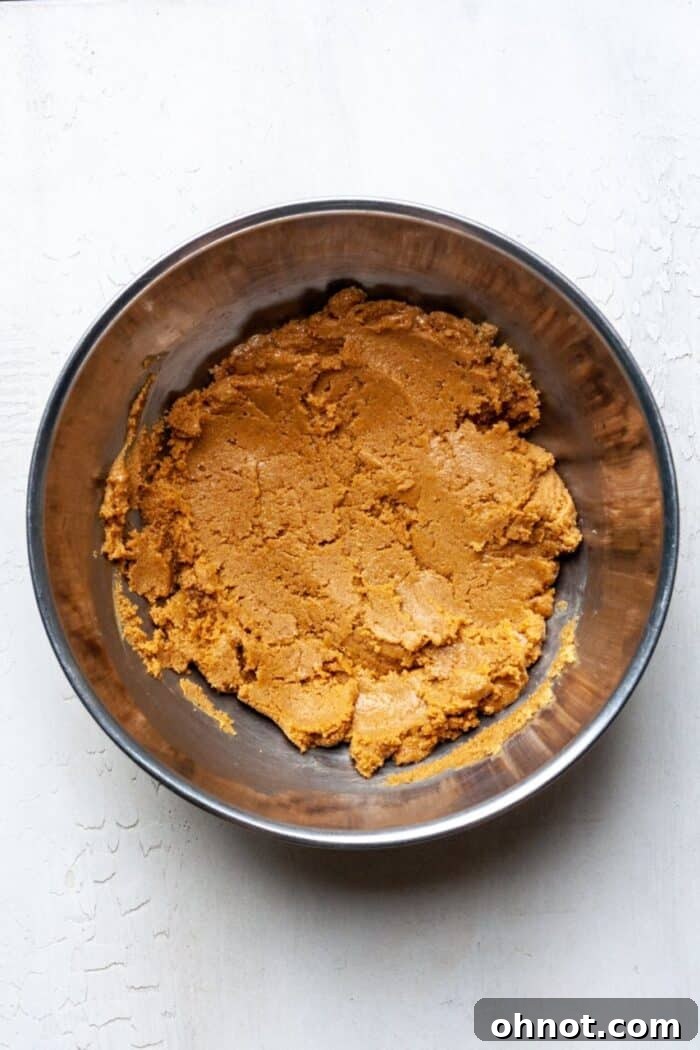 Peanut butter and brown sugar mixture being creamed in a mixing bowl, showing its smooth consistency