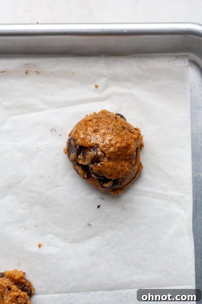 Scooped balls of Vegan peanut butter cookie dough placed evenly on a parchment-lined baking pan