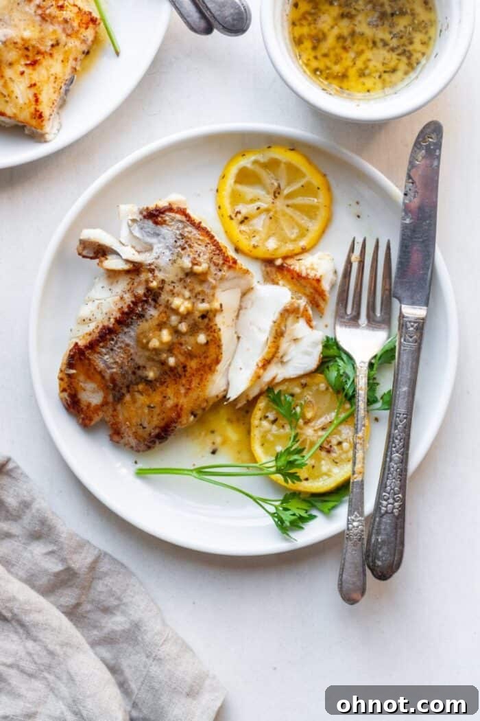 Close-up of pan-seared sea bass with vibrant lemon slices in a skillet.