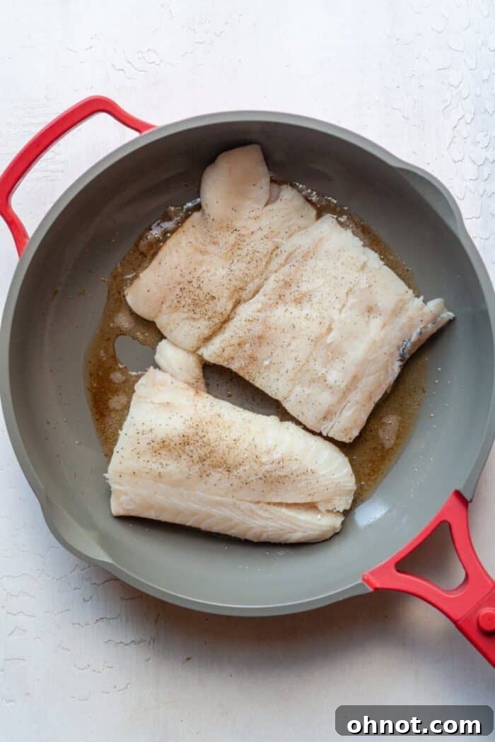 Chilean sea bass filets cooking skin-side down in a hot skillet.