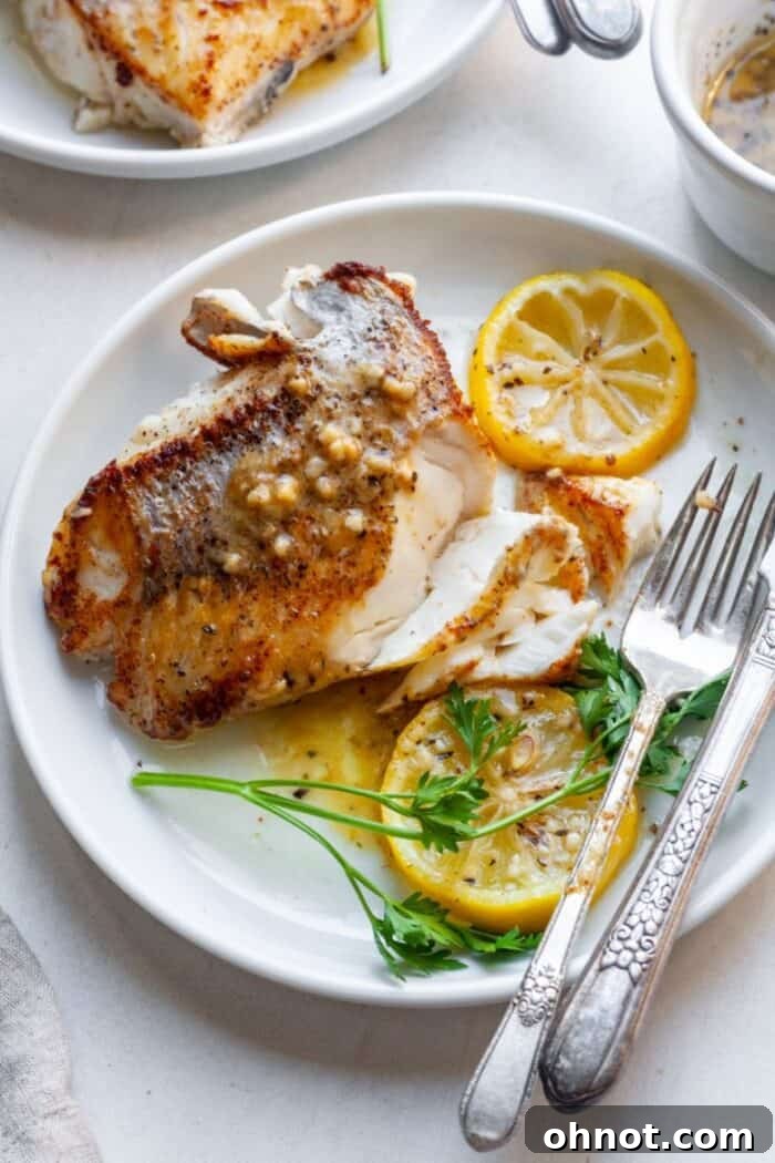 Plated pan-seared Chilean sea bass garnished with fresh herbs and lemon.