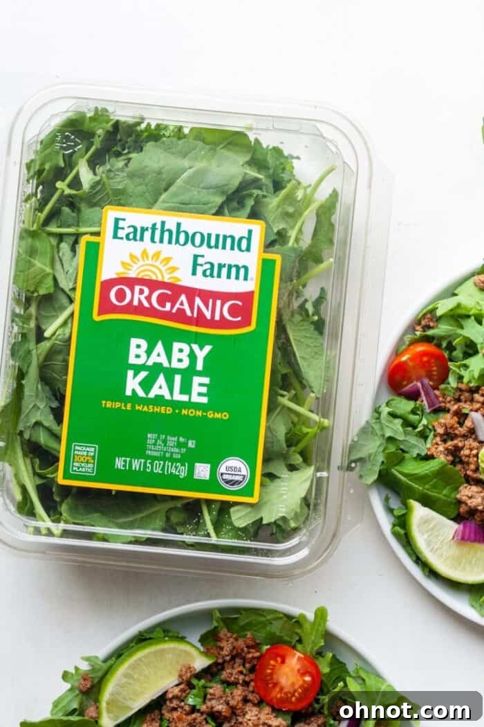 Fresh baby kale forming the vibrant green base of a healthy taco salad, ready for delicious toppings.