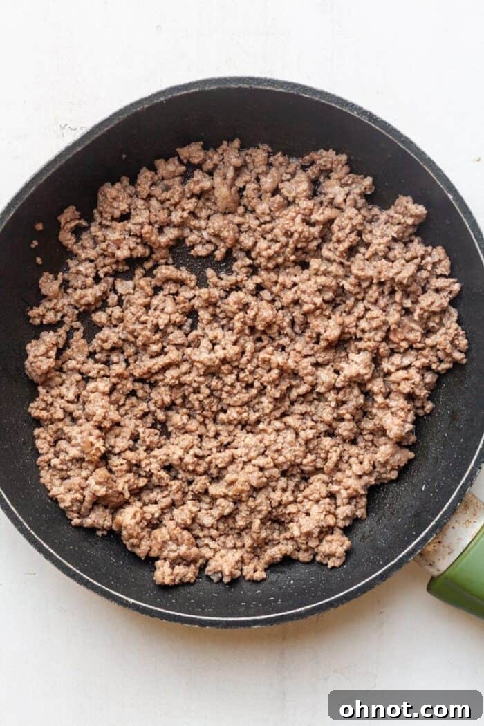 Cooked and crumbled taco meat in a skillet after excess grease has been drained.