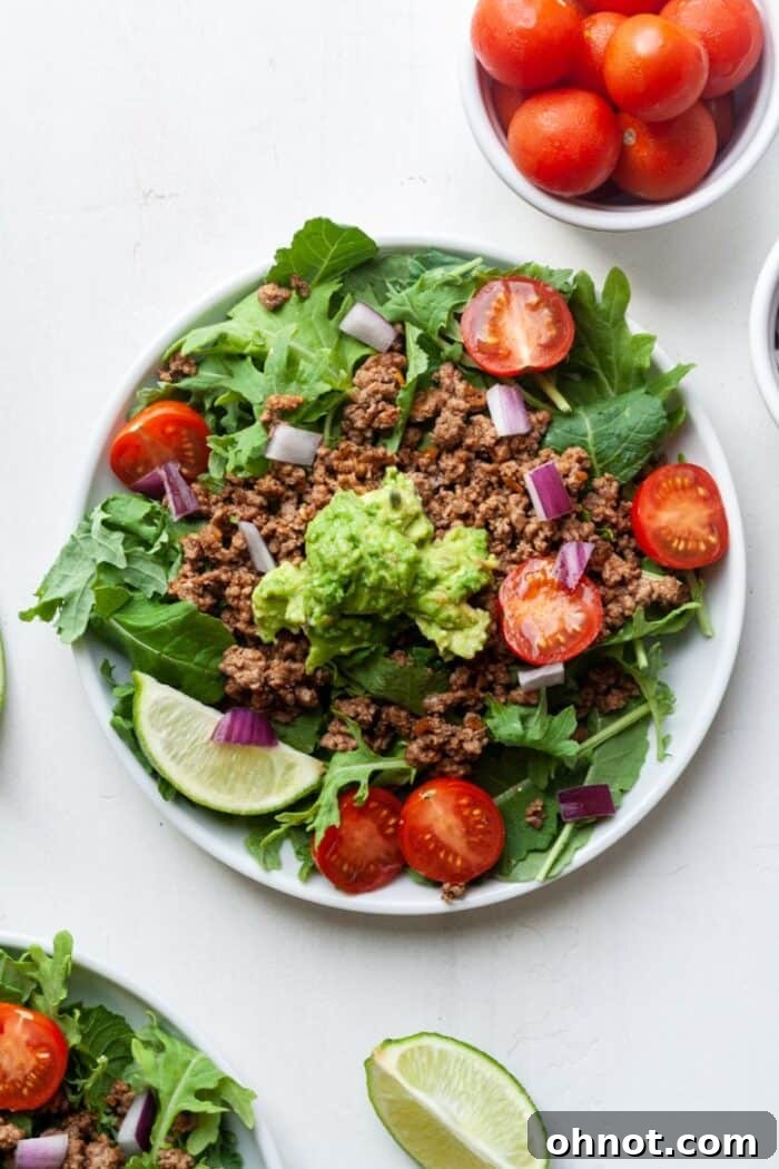 Fully assembled Paleo taco salad on a plate, featuring seasoned meat, creamy avocado, and vibrant fresh vegetables.
